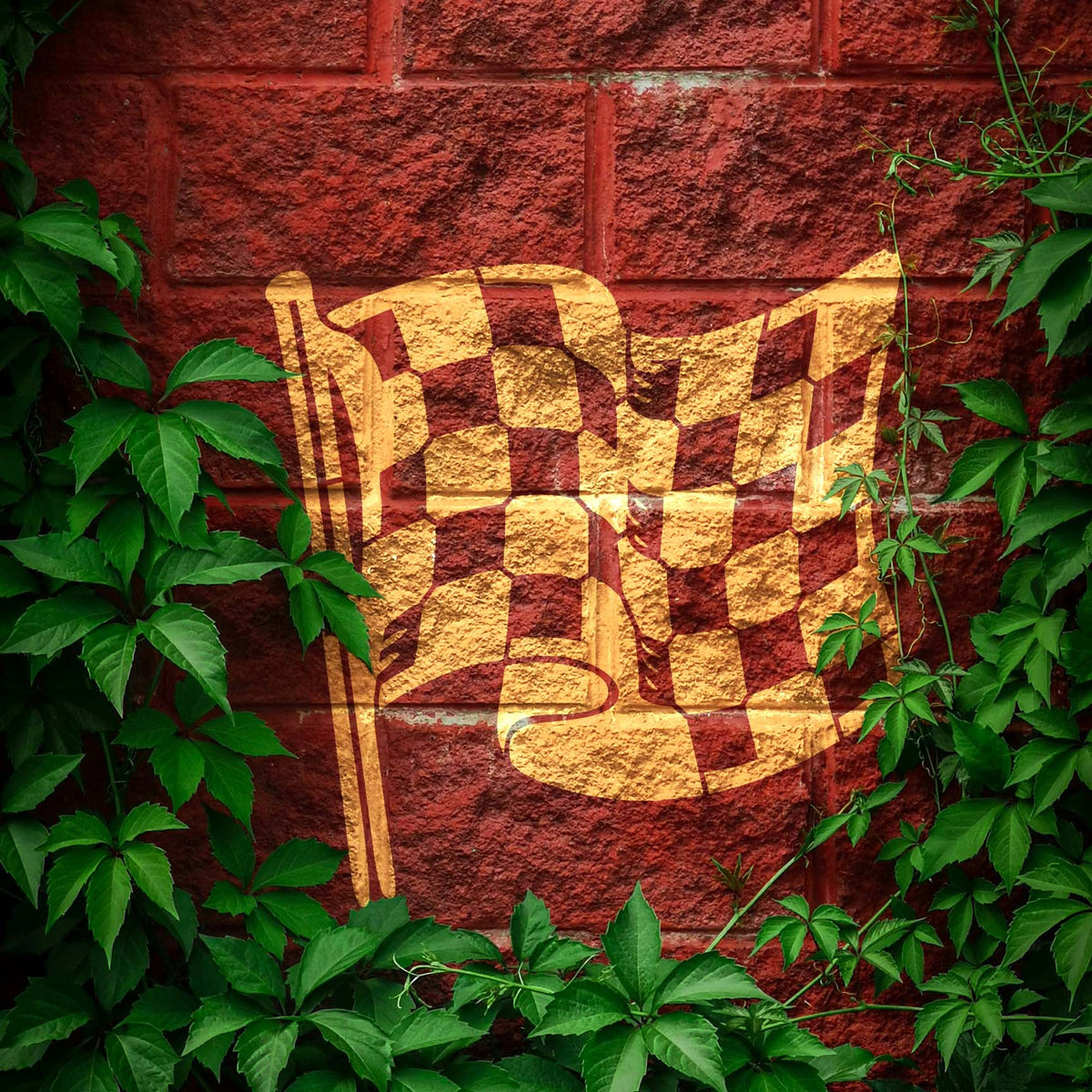 Checkered Racing Flag Stencil waves in gold across a red brick wall framed by green vines.