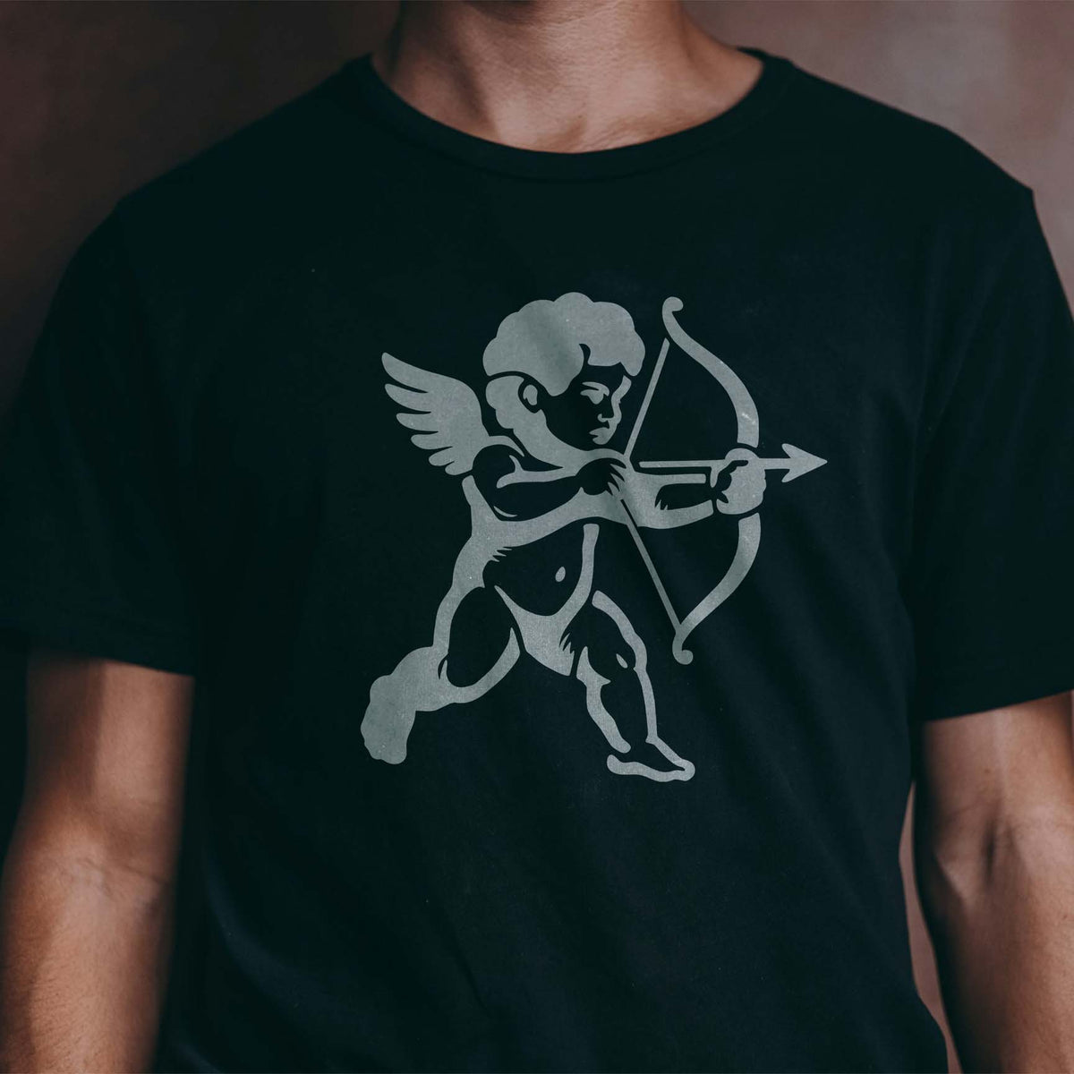 Cupid Cherub stencil with a winged cherub drawing a bow and arrow printed on a black T-shirt