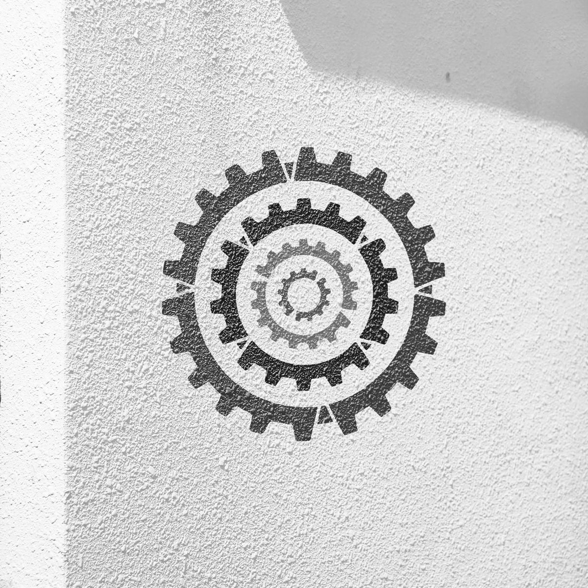 Concentric Cogs stencil featuring layered circular gears in black and gray on textured white wall
