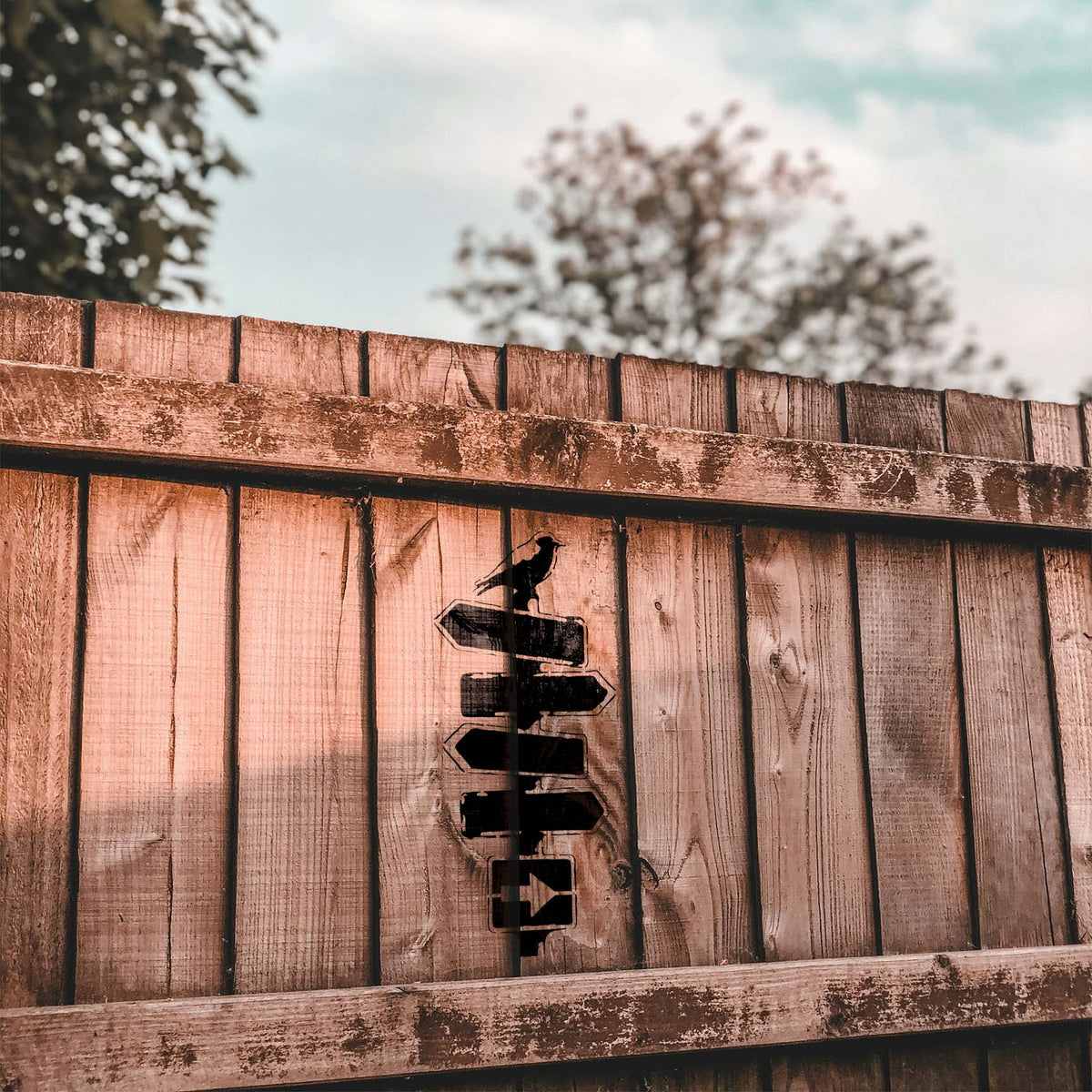 Crow on Rustic Signpost Stencil shown in black on a weathered wooden fence outdoors.