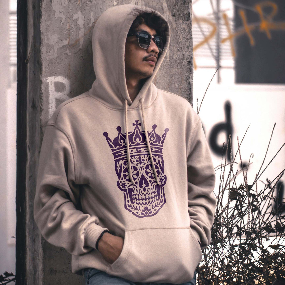 Crowned Sugar Skull Stencil adds an ornate purple skull and crown graphic to a beige hoodie.