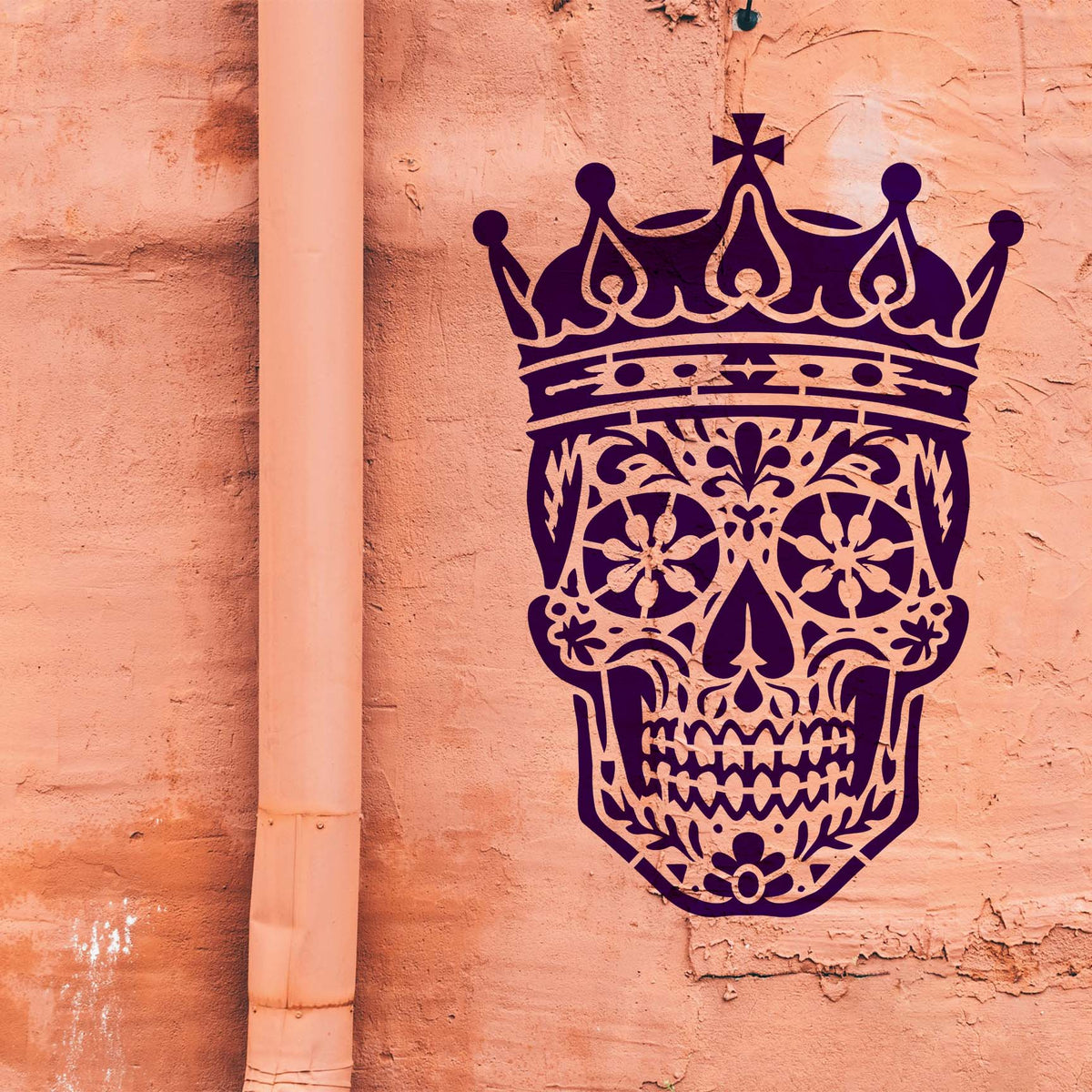 Bold purple Crowned Sugar Skull Stencil stands out against a weathered salmon-colored wall.