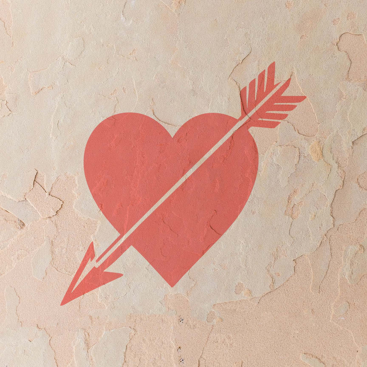 Cupid Heart with Arrow Stencil painted coral red across a weathered textured stucco wall