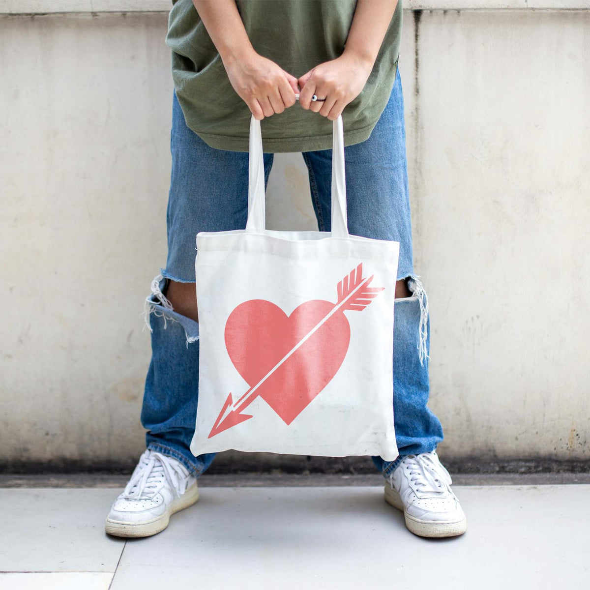 White tote bag displays the Cupid Heart with Arrow Stencil in a soft coral pink design