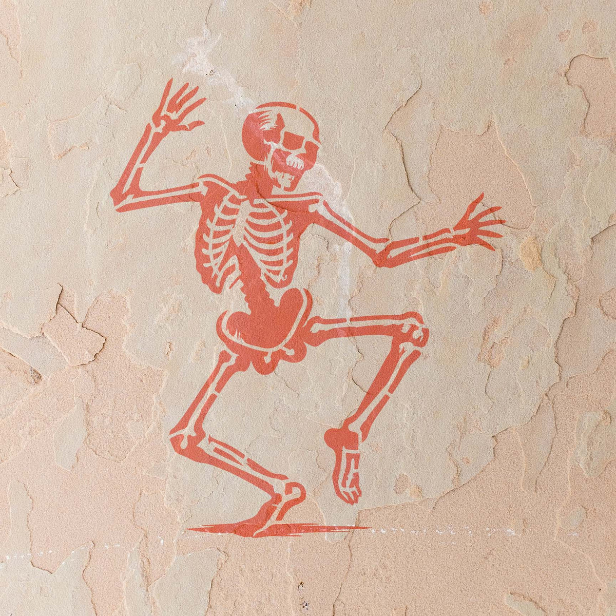 Dancing Skeleton Halloween Stencil leaps across a weathered stucco wall in coral paint