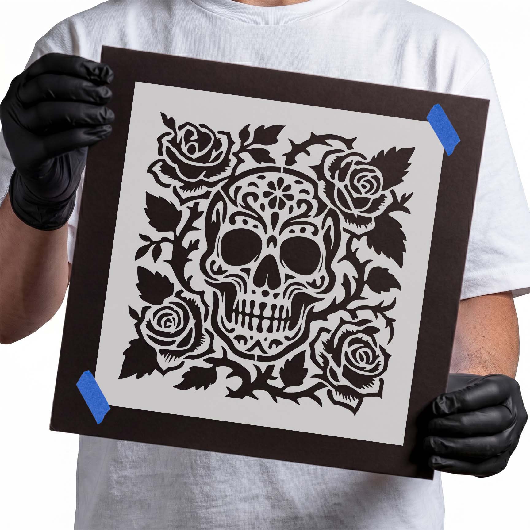 Sugar skull stencil surrounded by four roses and decorative leaves
