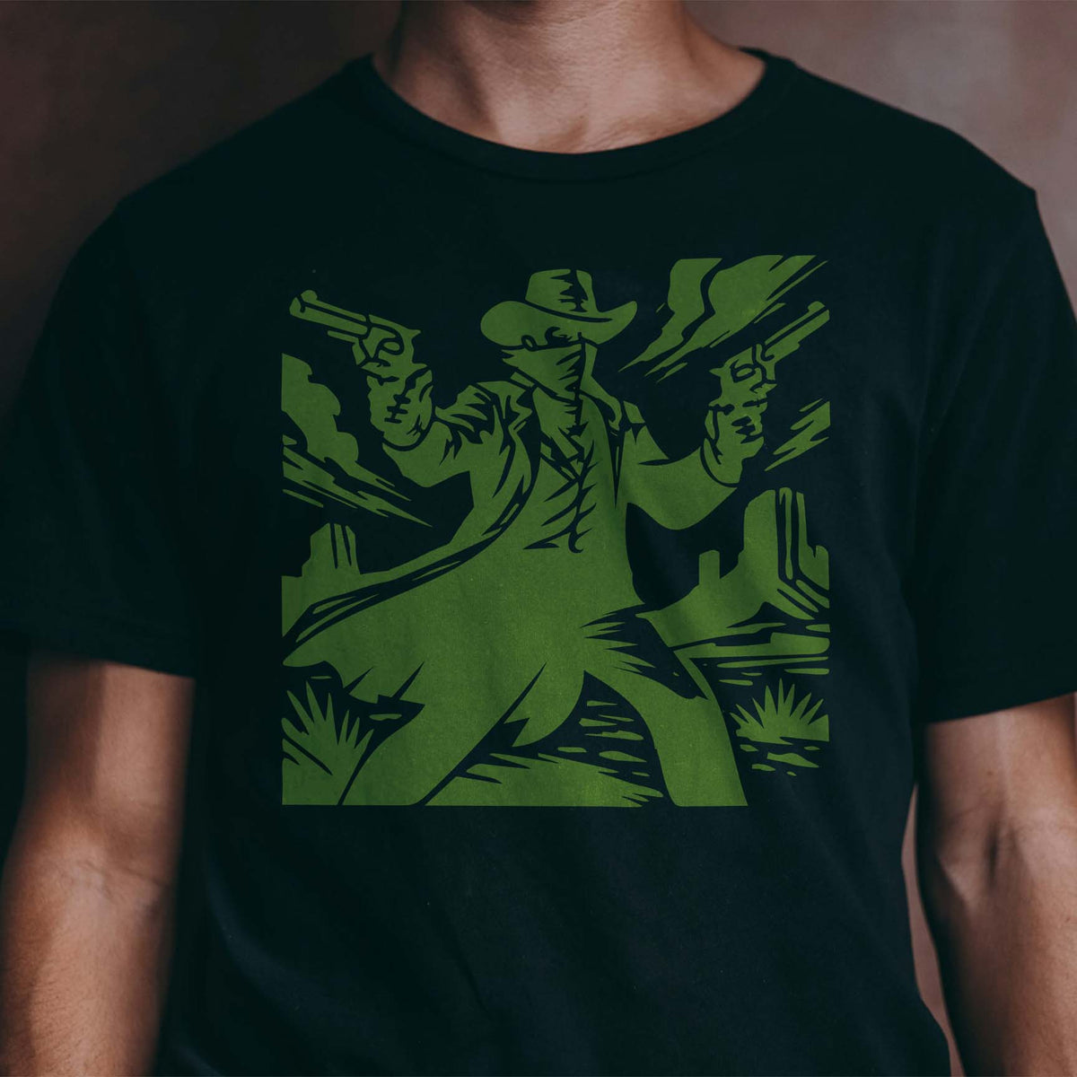 Desert Gunslinger Stencil printed in green across the front of a black T-shirt.