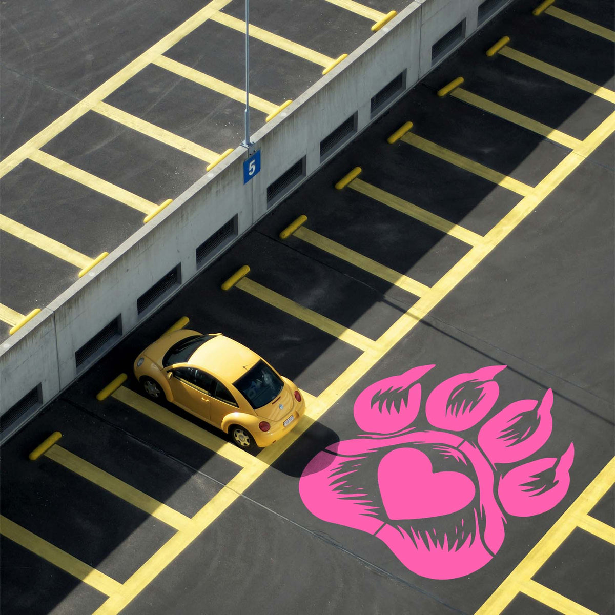 Across dark pavement, the Dog Paw Print Heart Stencil stands out in pink beside yellow parking lines