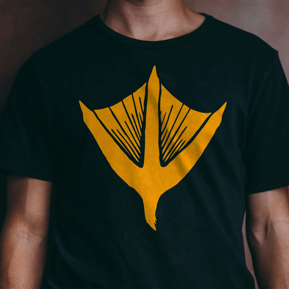 A bold yellow Duck Track Stencil displays a detailed webbed footprint across the front of a black T-shirt.