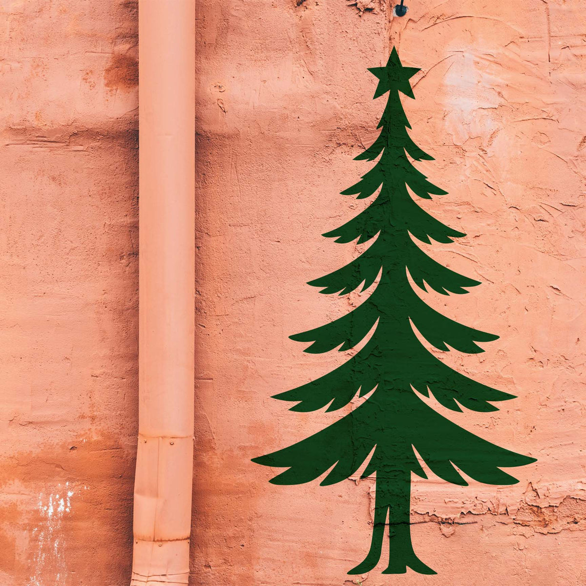 Elegant Slim Christmas Tree Stencil shown in green on a peach wall beside a drainpipe.