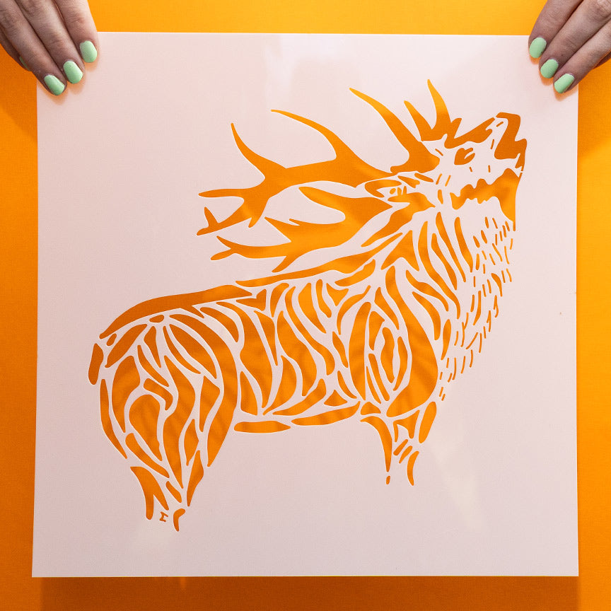 Highly detailed laser-cut elk stencil held against an orange background