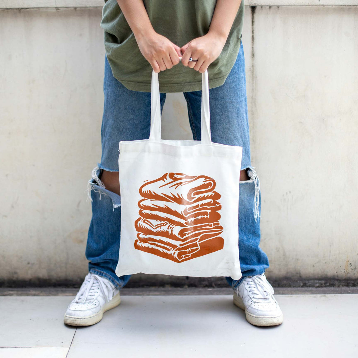 Folded Laundry Stack stencil printed orange on white tote bag