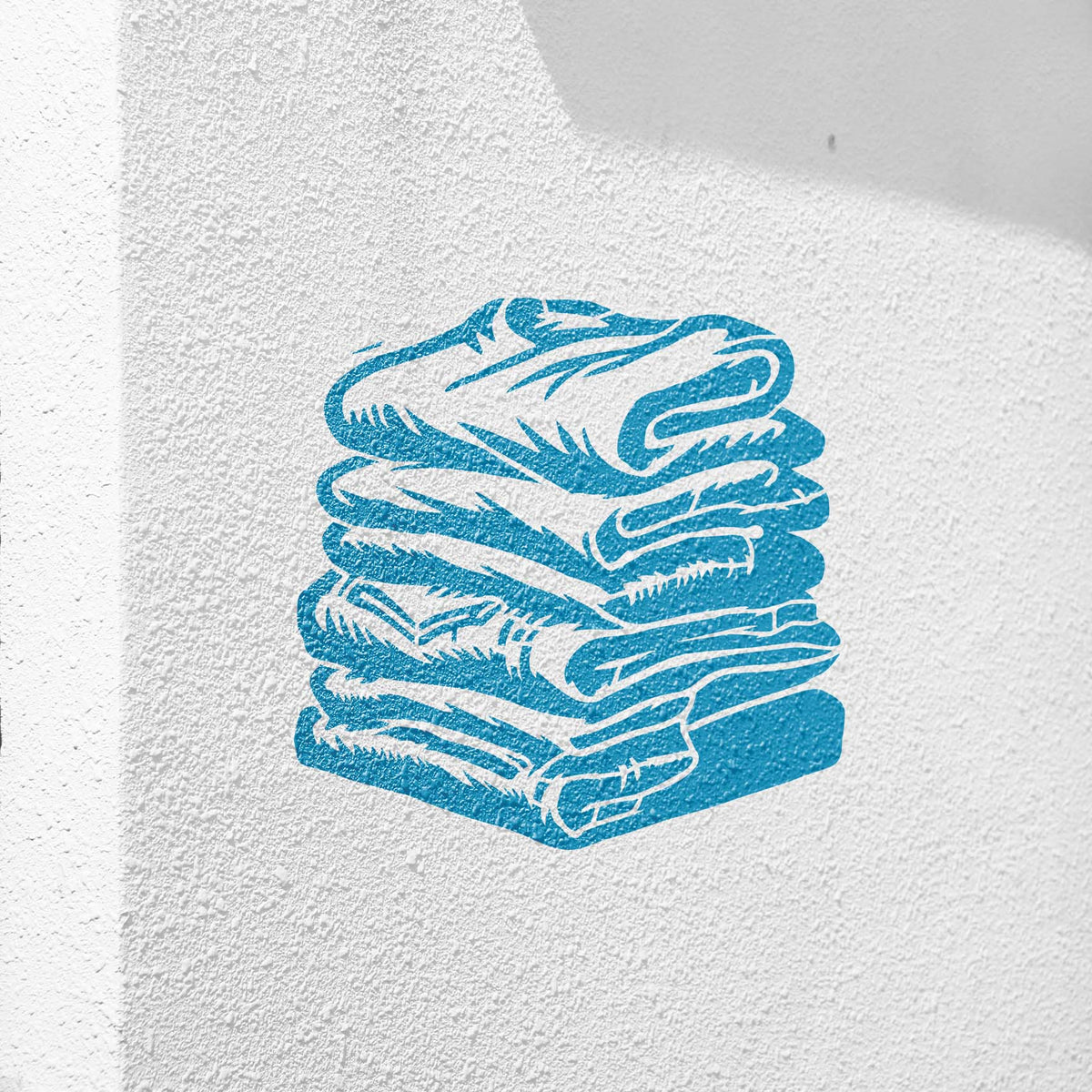 Folded Laundry Stack stencil painted blue on textured white wall