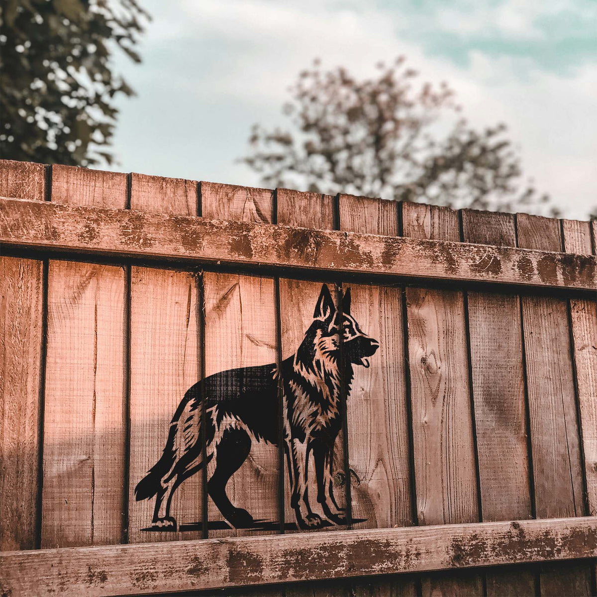 Rustic wooden fencing showcases the German Shepherd Profile Stencil with a watchful gaze and upright ears.