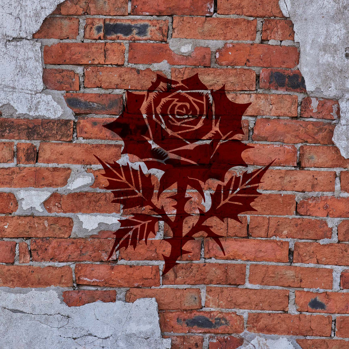 Gothic Rose Bloom Stencil shown in dark red on a weathered brick wall.