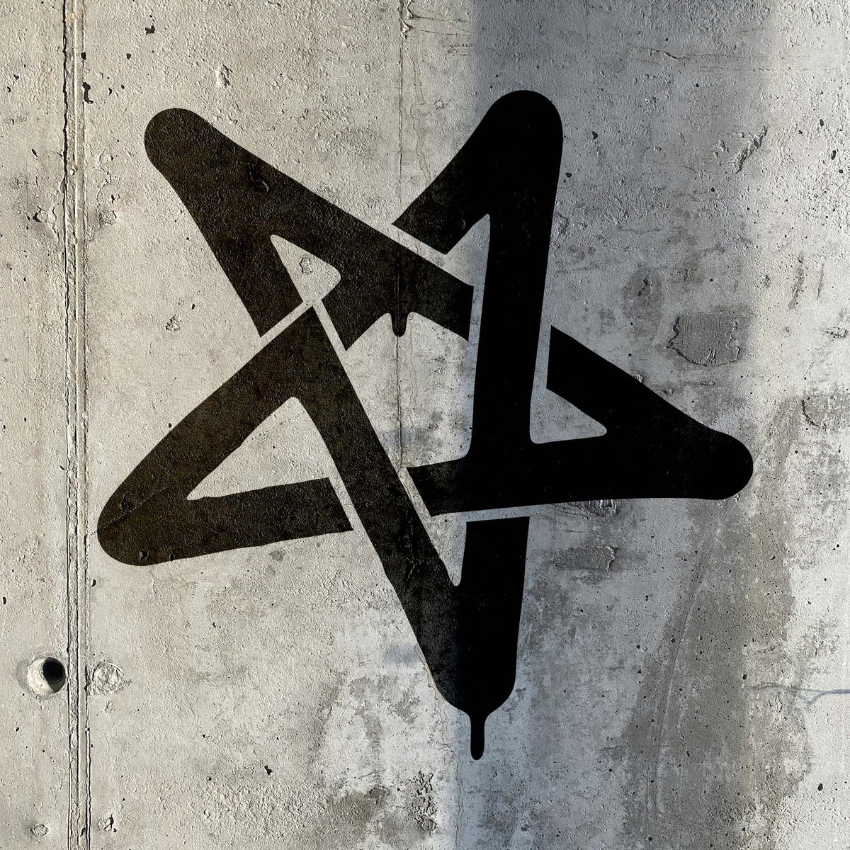 Graffiti Star Stencil painted in bold black across a raw concrete wall