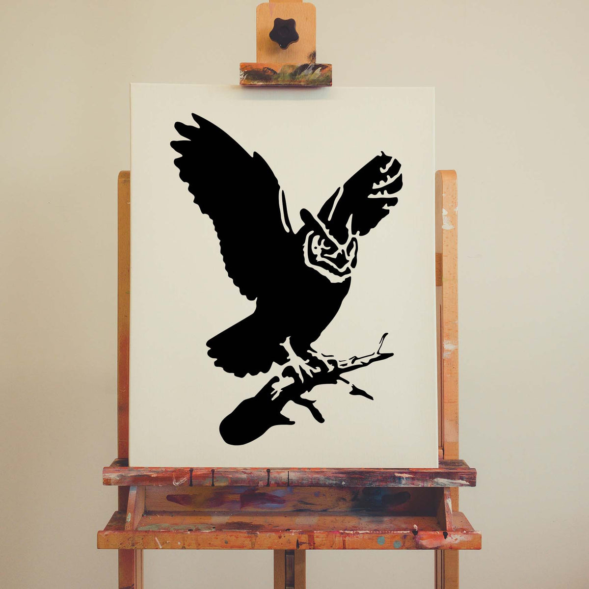 Great Horned Owl Stencil displayed in black on a white canvas set on a wooden easel.