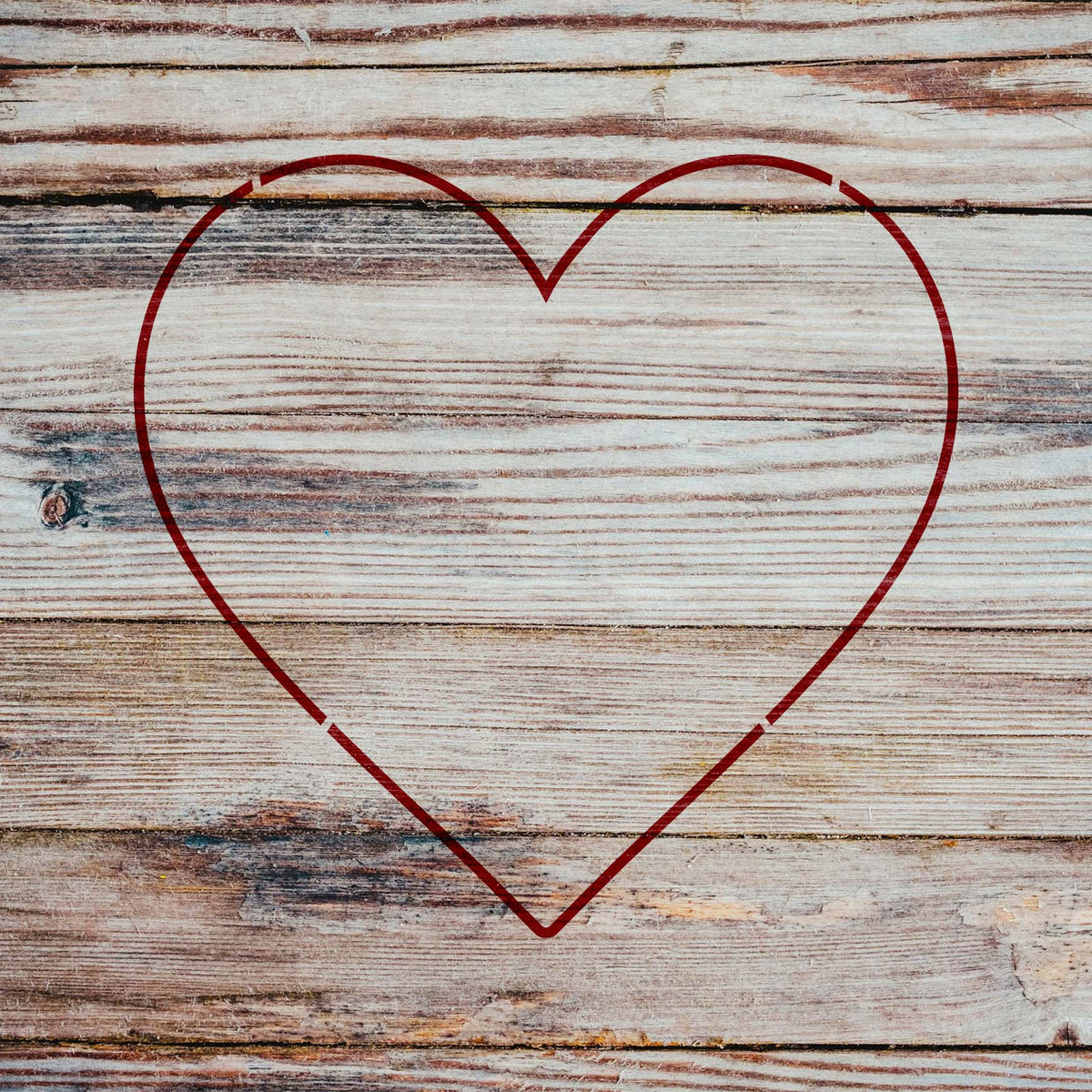 Rustic wood frames the Heart Outline Stencil as a crisp red heart against weathered planks