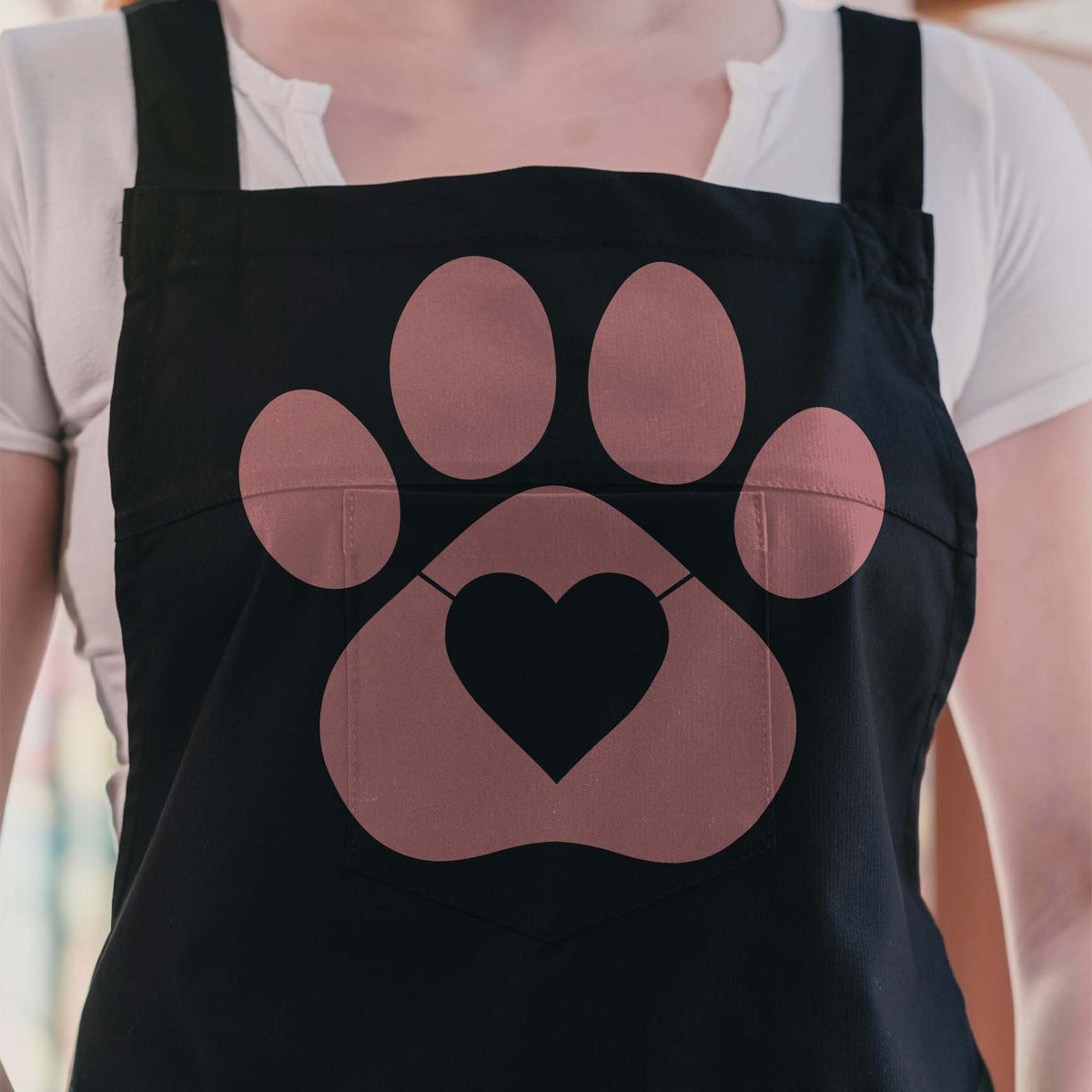 Heart Paw Print Silhouette Stencil in muted pink decorates the front of a black apron
