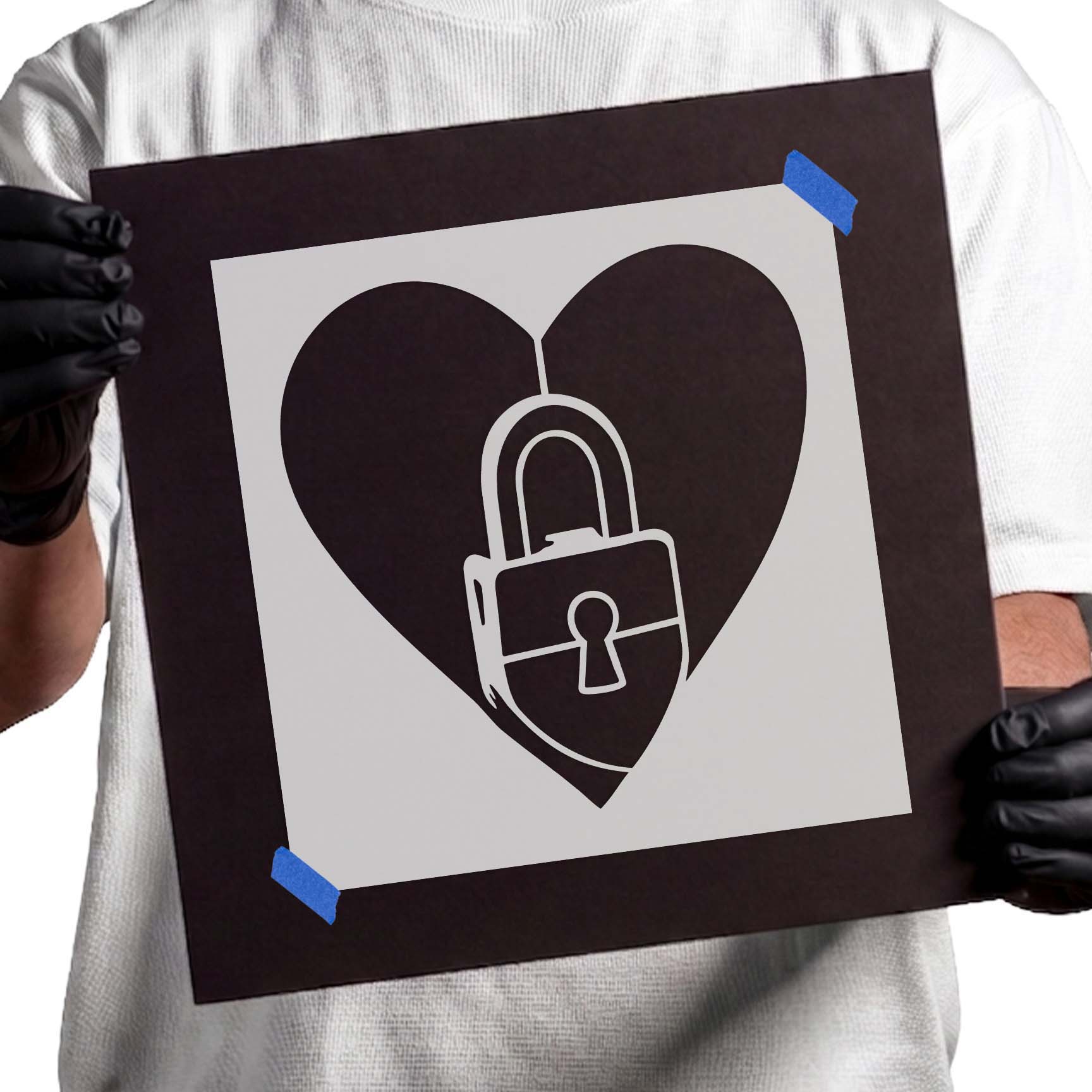 Gloved hands holding Love Lock Heart Stencil taped to black cardboard