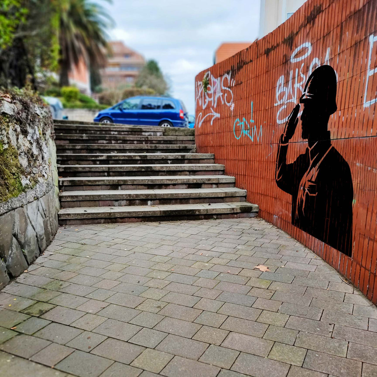 Urban brick wall features the Honor Guard Salute Stencil beside an outdoor stairway