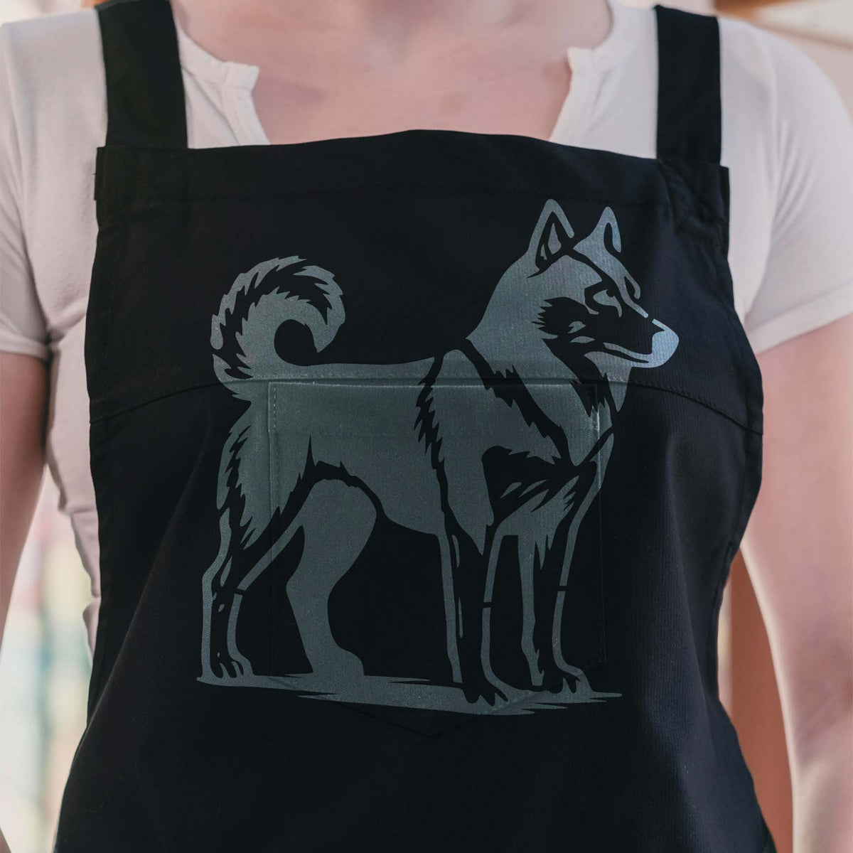 Husky Dog Stencil in gray on a black apron, featuring pointed ears, a curled tail, and thick fur.
