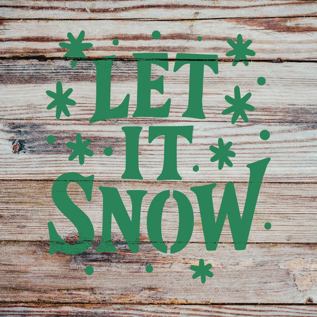 Rustic wood displays the Let It Snow Hand Lettered Stencil with green text and scattered snowflakes.