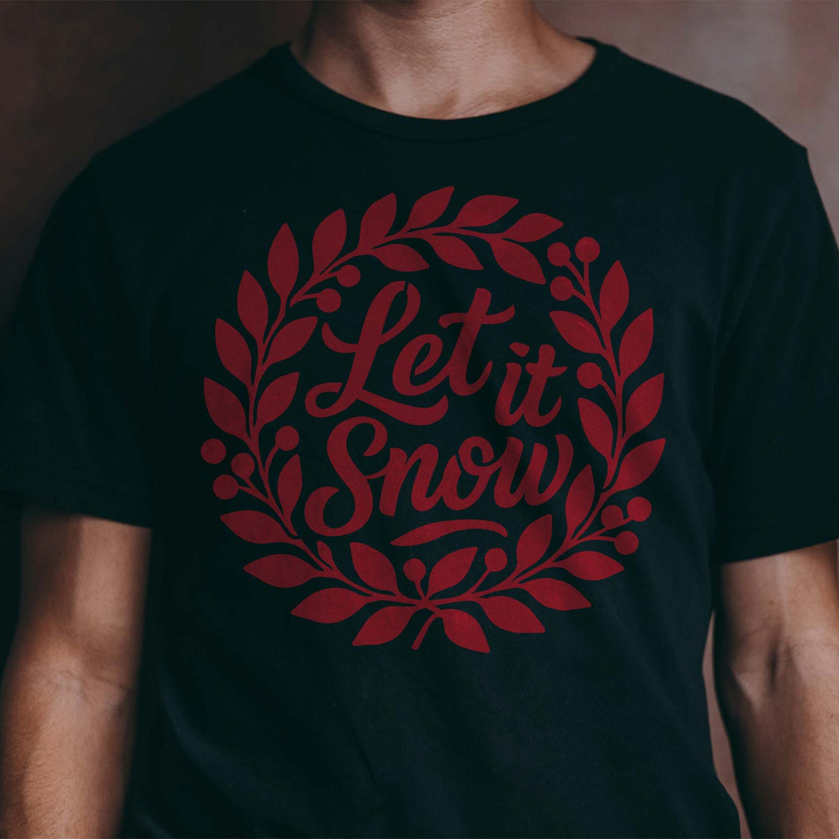 Red Let It Snow Holiday Wreath Stencil creates a leafy winter wreath on a black shirt.