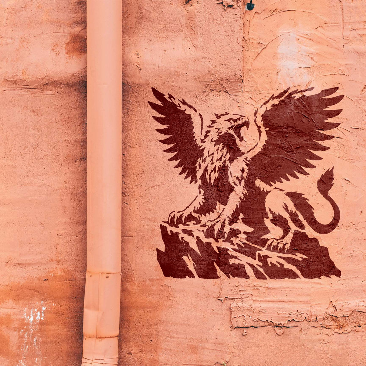Majestic Griffin on Cliff Stencil depicts a fierce winged griffin perched on rock against a textured wall.