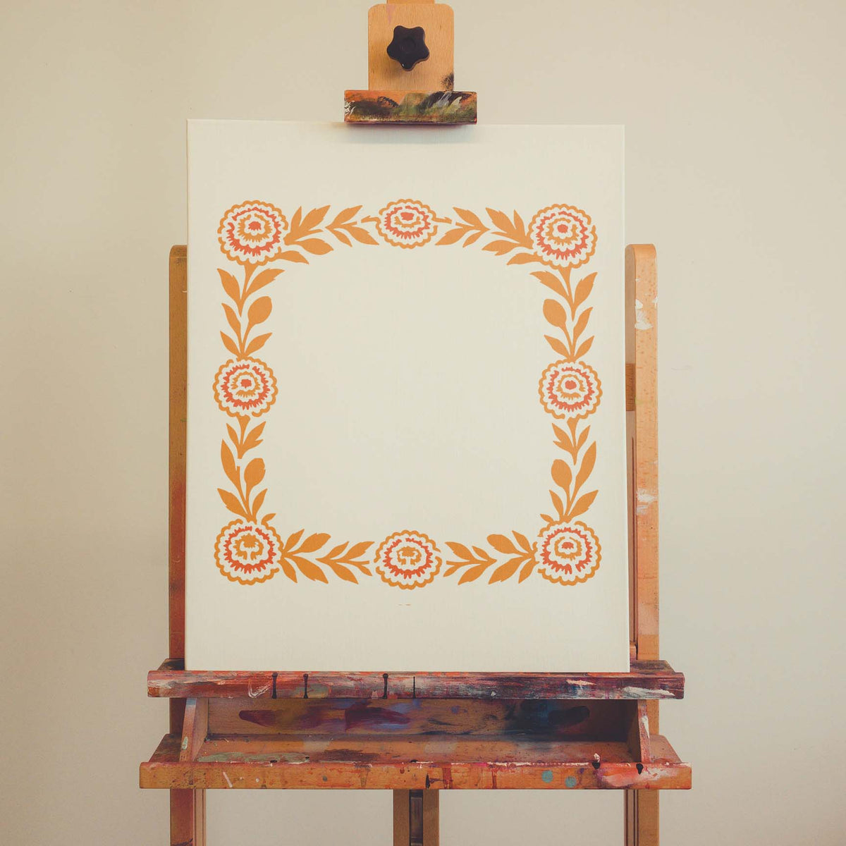 Floral Marigold Border stencil blooming in orange on an artist canvas