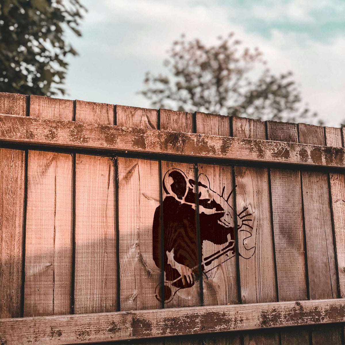 Rustic wood fence carries the Mechanic Rat with Wrench Stencil in a dark brown finish