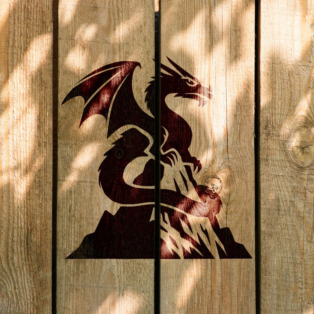 Sunlit wood planks display the Mountain Peak Dragon Stencil with a coiled winged dragon