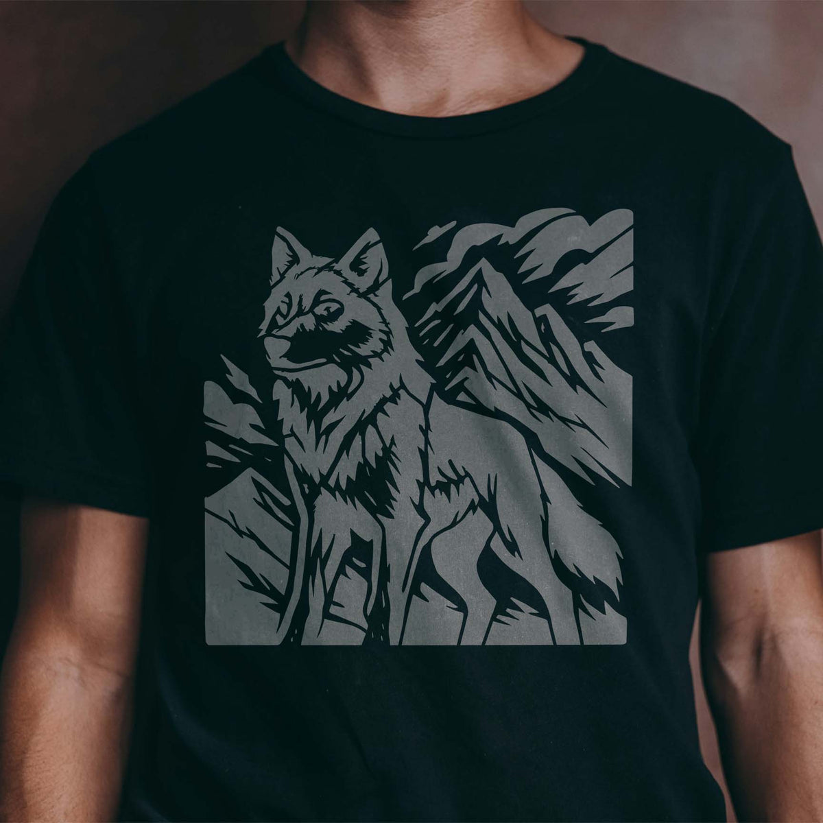 Mountain Wolf Wilderness Stencil shows a lone wolf and rugged peaks in gray on a black shirt.