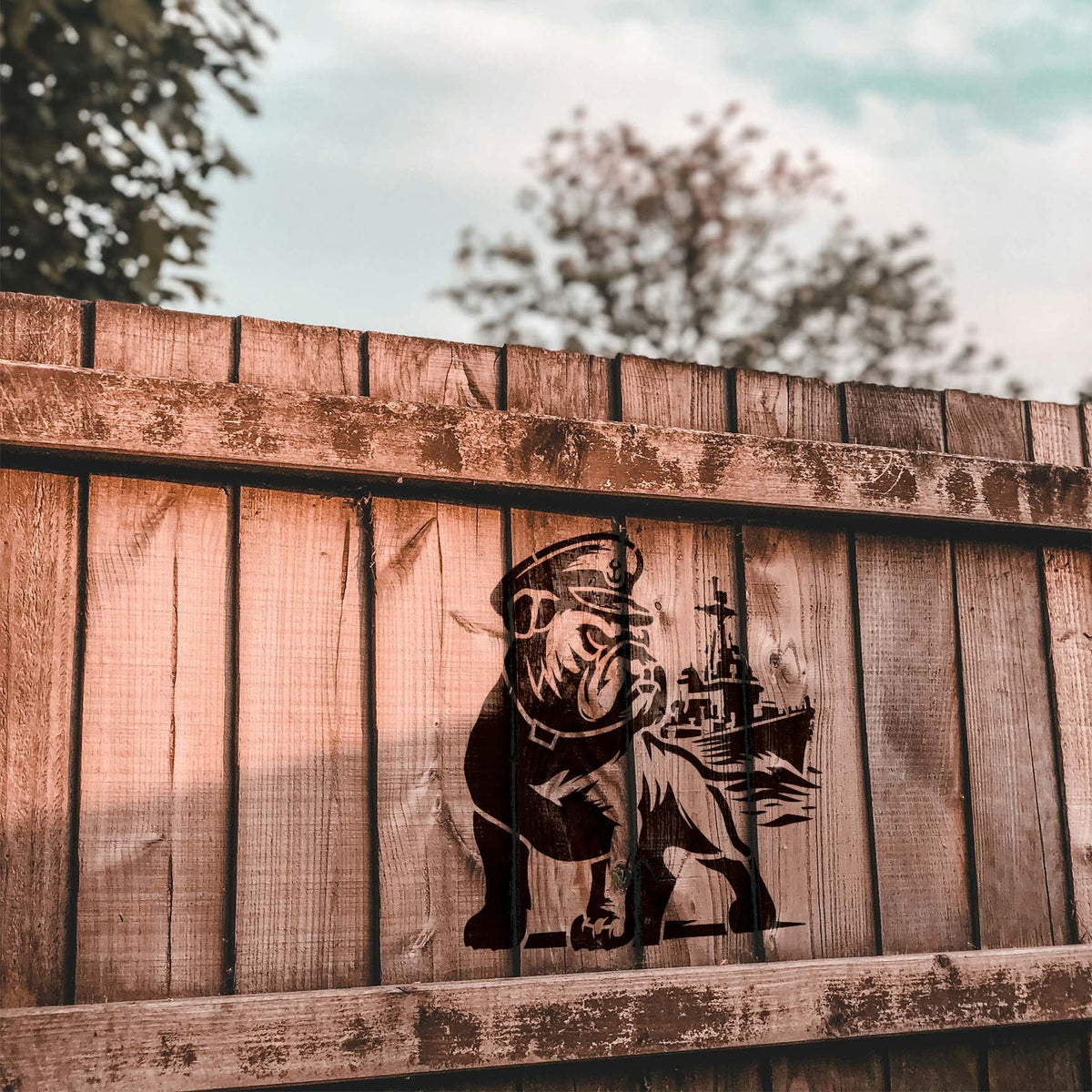 Against rustic wooden planks, Naval Bulldog & Battleship Stencil depicts a bulldog and naval ship.