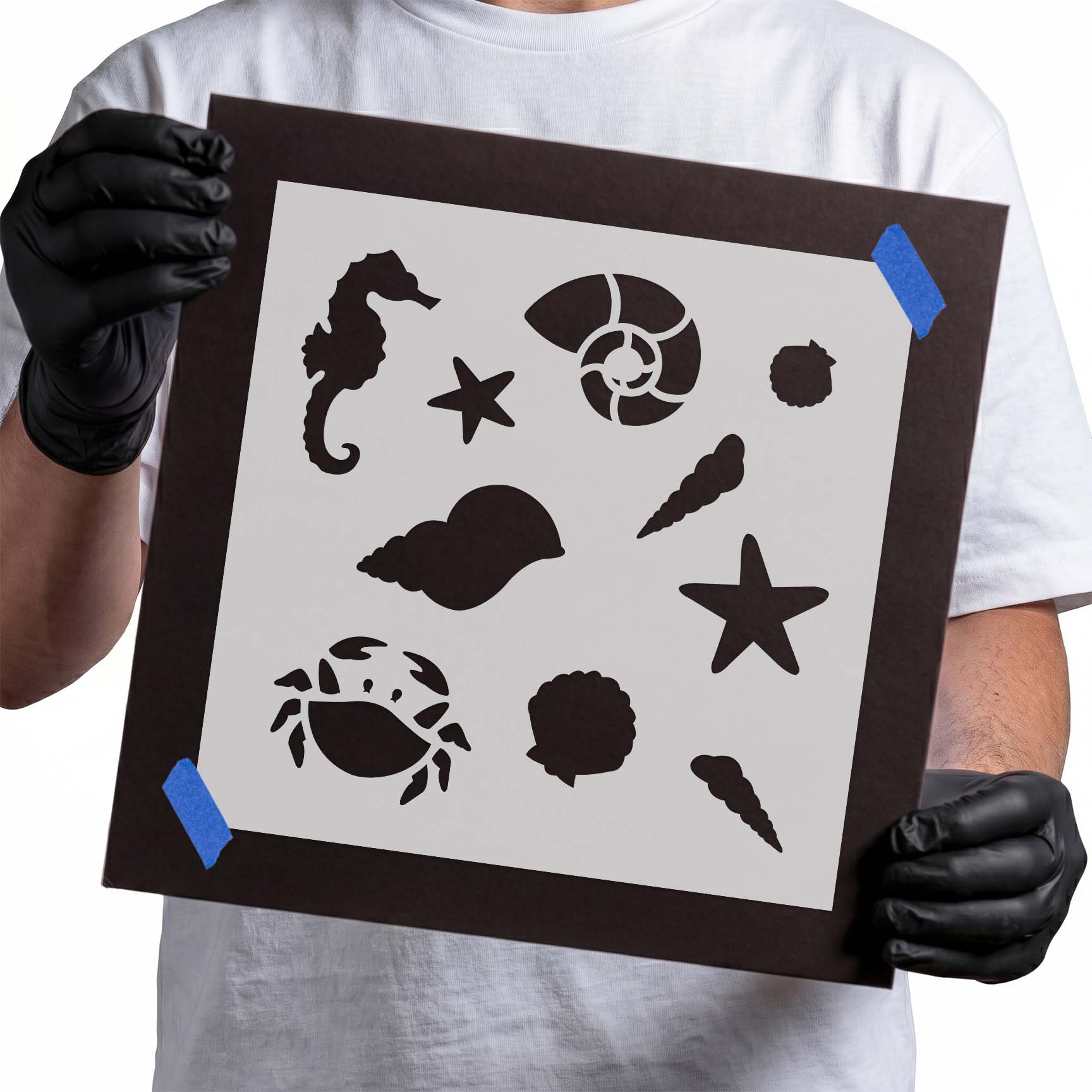 Person holding a reusable Ocean Symbols Pattern Stencil taped to cardboard