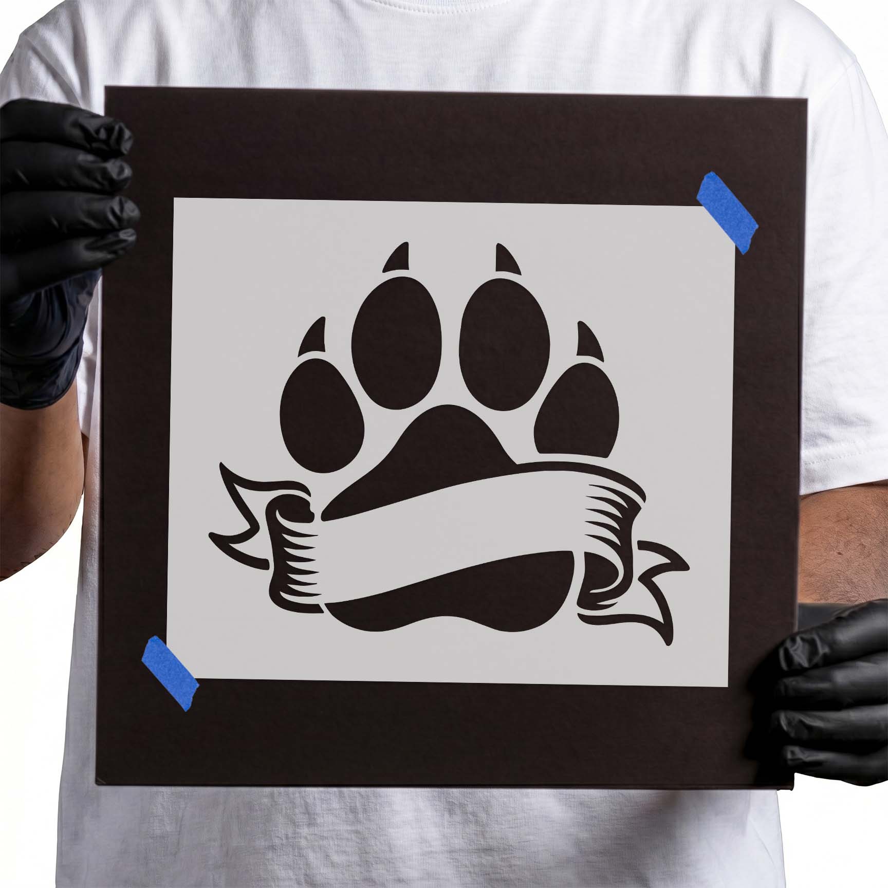 Person holding Blank Banner Paw Print Stencil taped to black cardboard