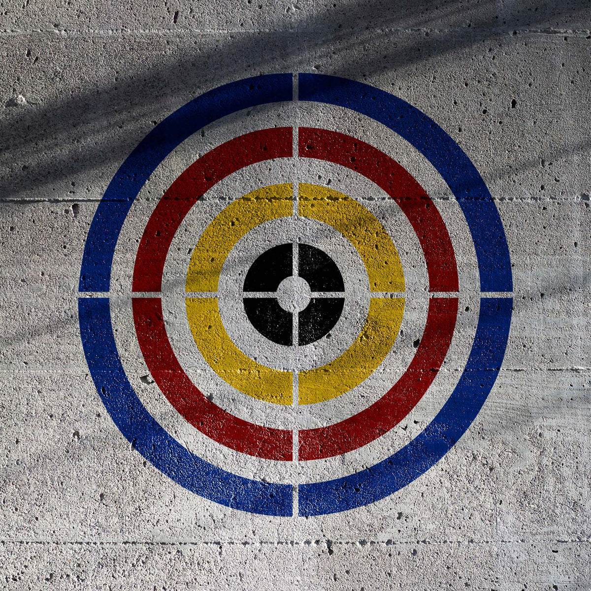 Bold Precision Concentric Target Stencil painted in blue, red and yellow on rough concrete