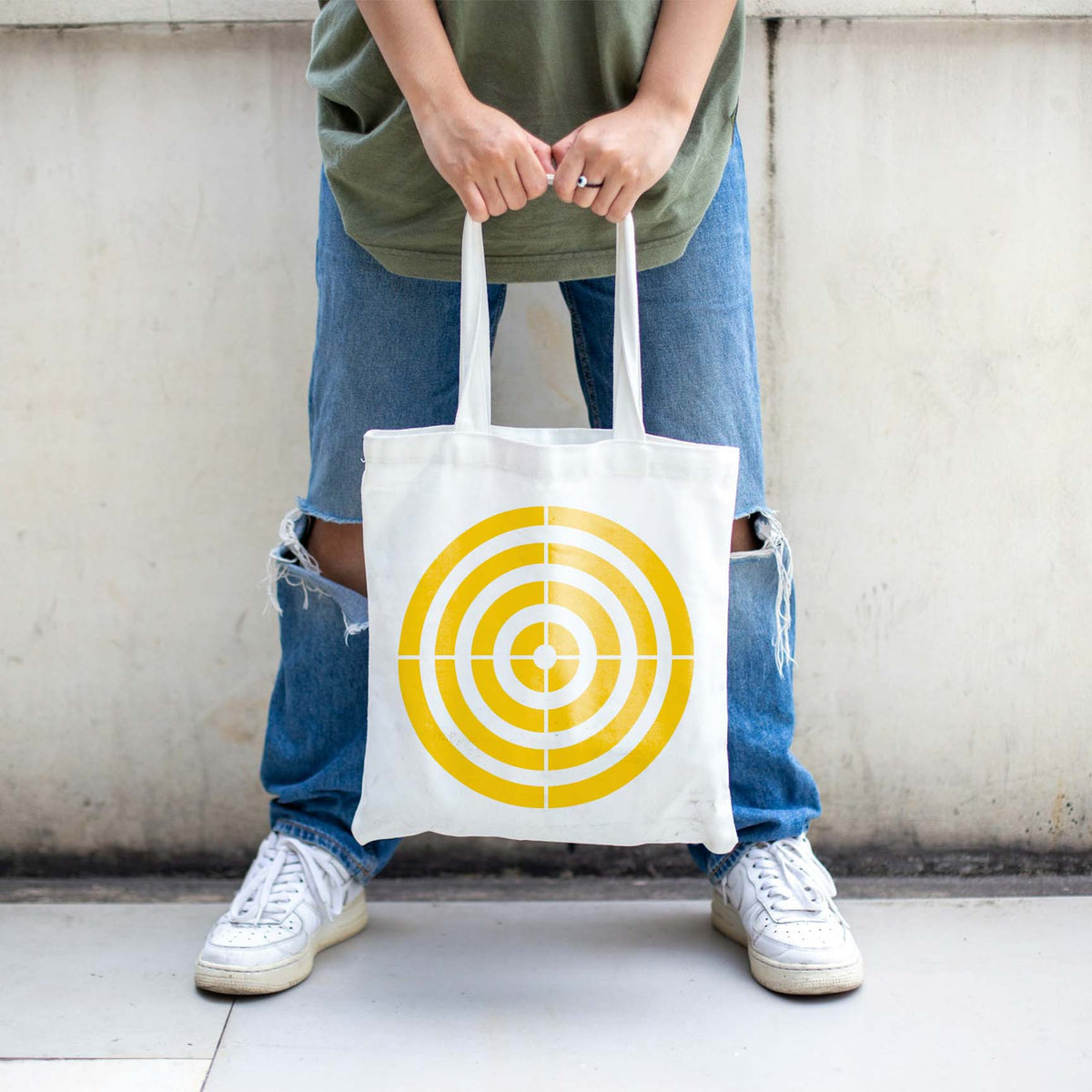 A white tote bag displays the Precision Concentric Target Stencil in sunny yellow rings