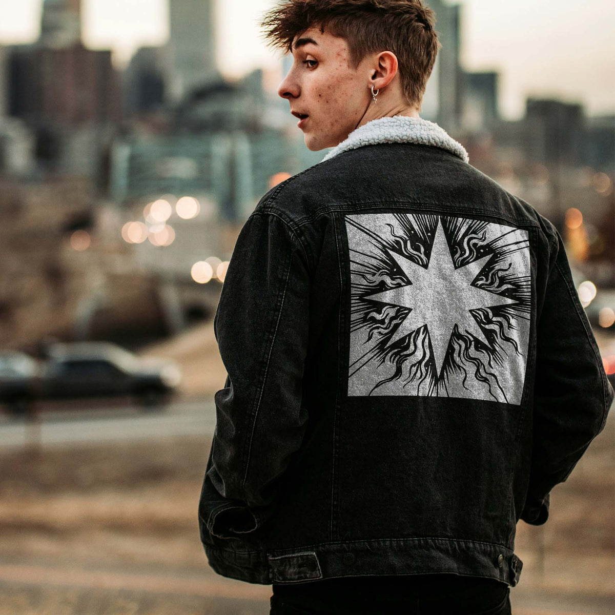 A bold silver Radiant Eight-Point Star Stencil with dramatic bursts adorns a black denim jacket.