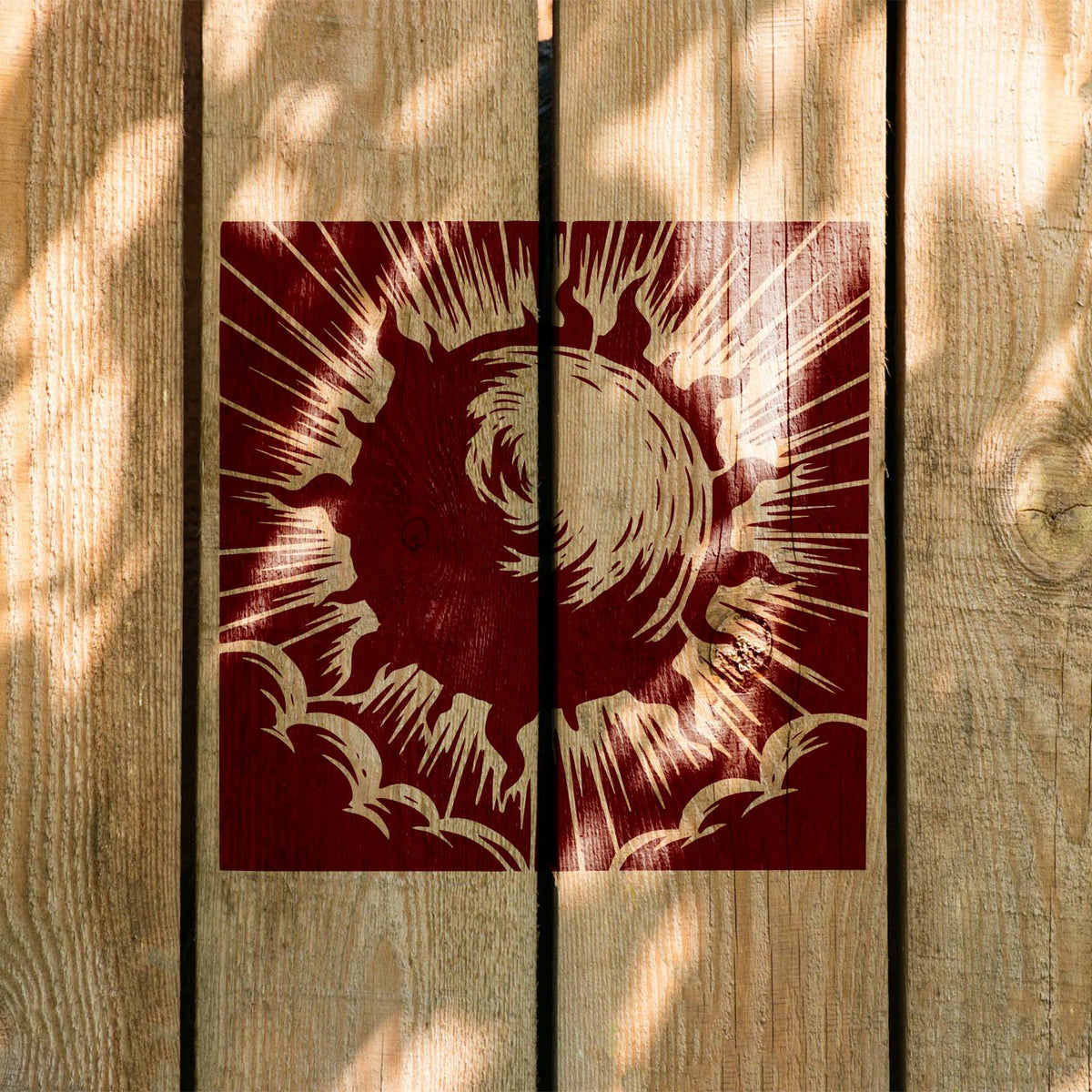 Across natural wood, the Radiant Solar Burst Stencil displays sweeping rays and cloud details