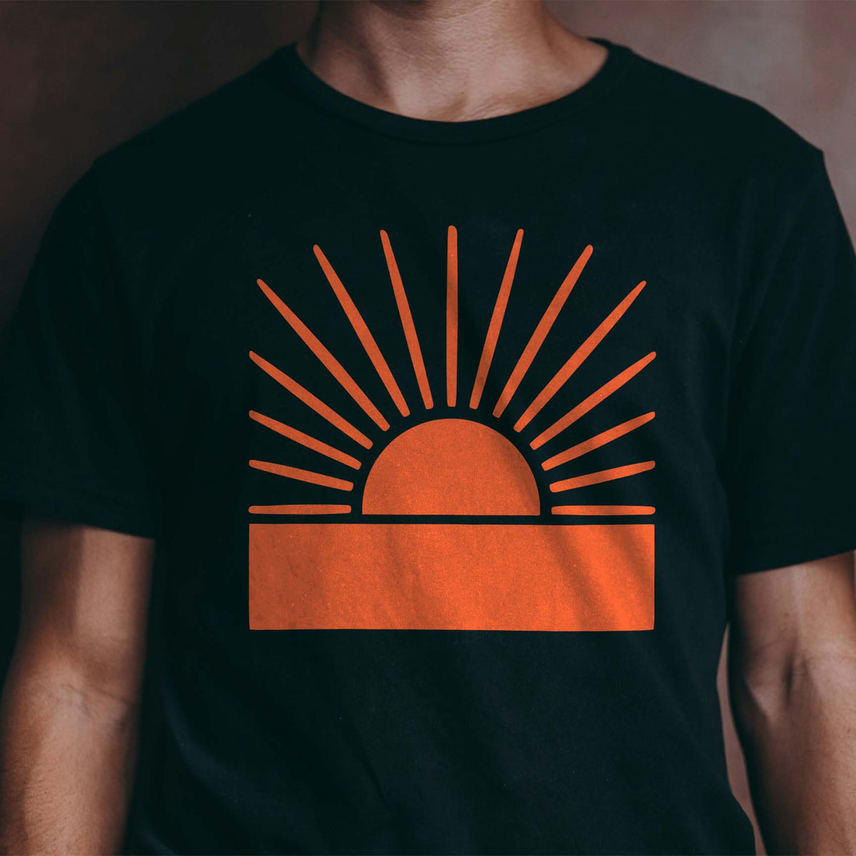 Vibrant orange sunbeams from the Radiant Sunrise Horizon Stencil glow against a classic black t-shirt.