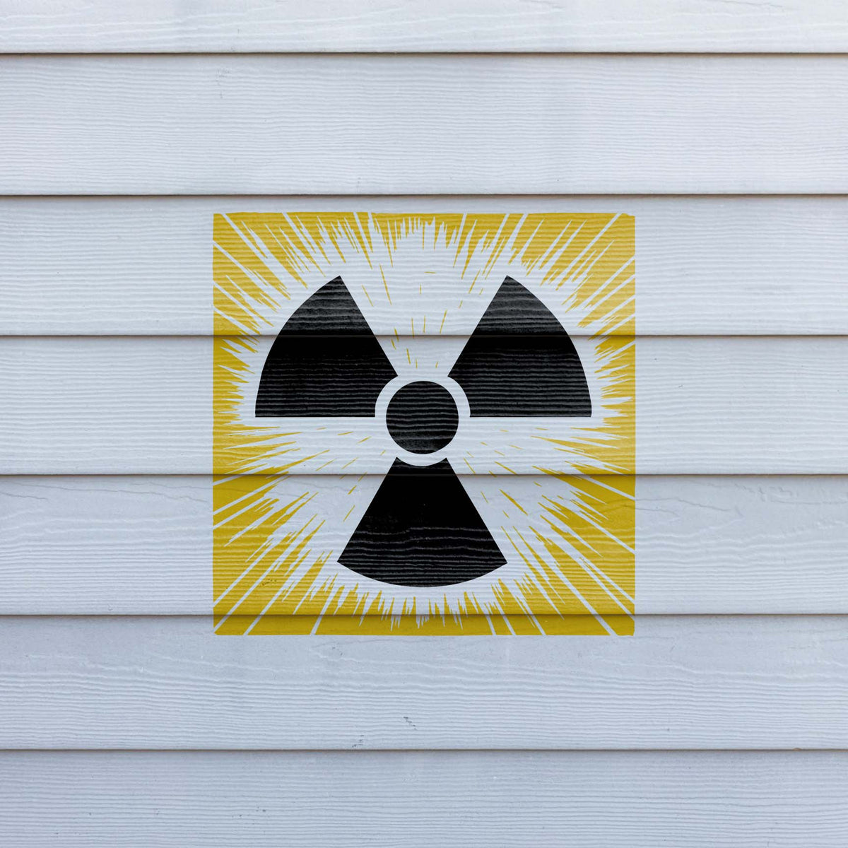 Yellow and black Radiation Trefoil Burst Symbol Stencil stands out on white exterior siding
