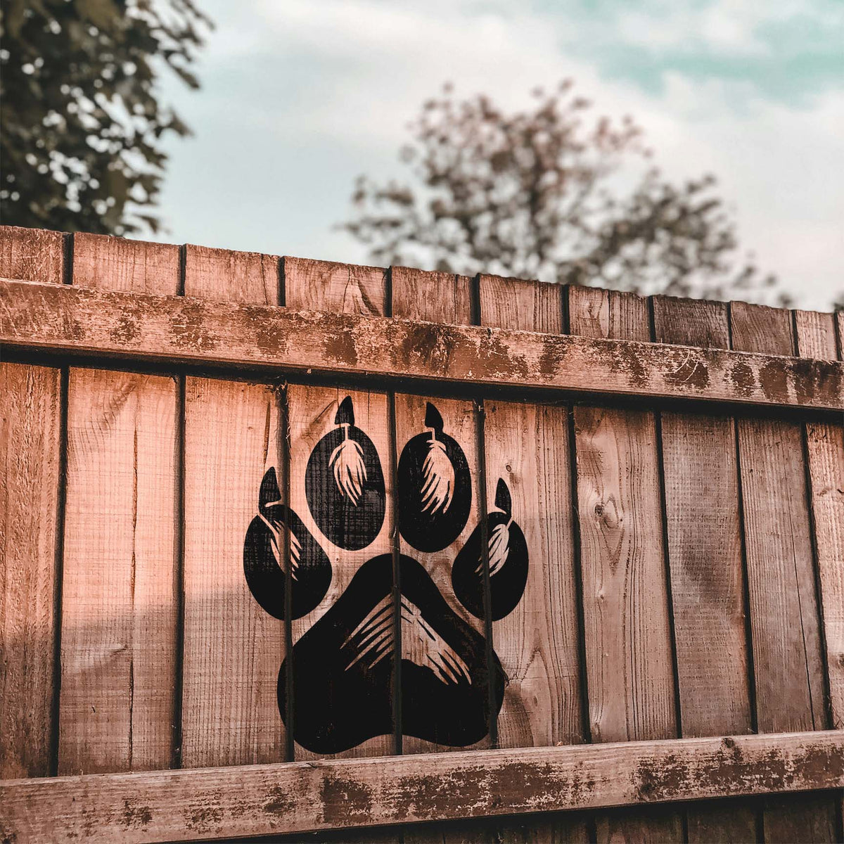 Realistic Dog Paw Print Stencil with detailed claws painted on a wooden fence