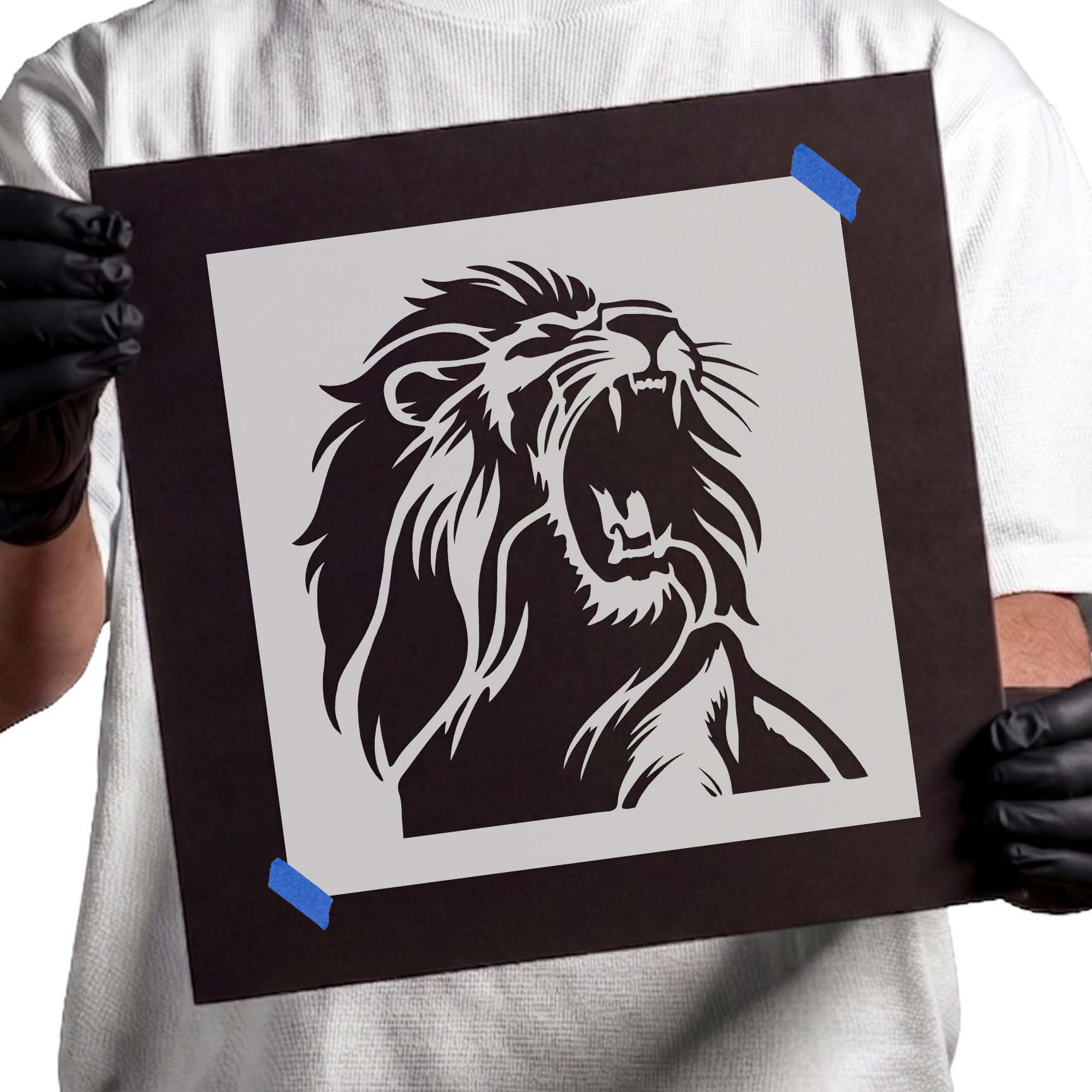 Gloved hands holding Roaring Lion Head Stencil taped to cardboard
