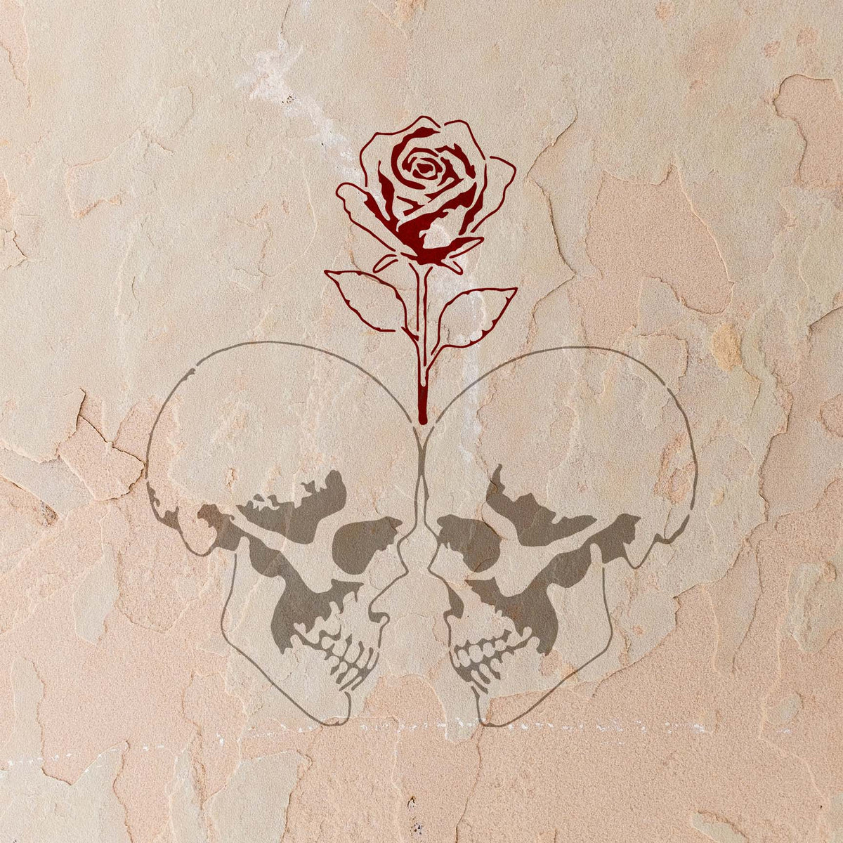 Rose Between Twin Skulls Stencil pairs mirrored skulls with a red rose on a weathered wall