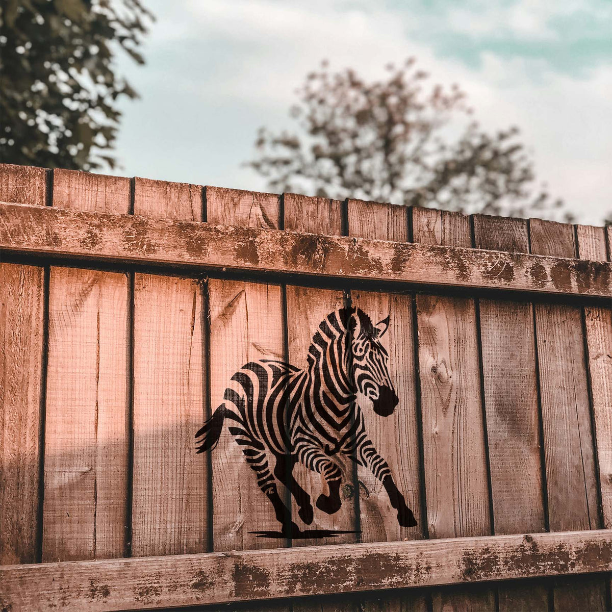 Running zebra stencil painted in black on a rustic wooden fence