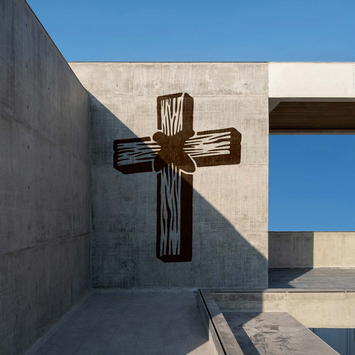 On a concrete wall, the Rustic Wooden Cross Stencil appears as a bold brown cross in an outdoor setting
