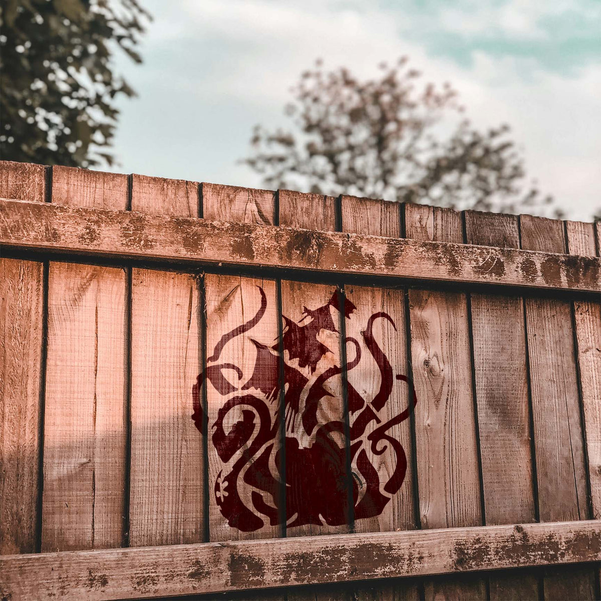 Sea Monster Attack Stencil covers a rustic wood fence with a bold nautical creature scene