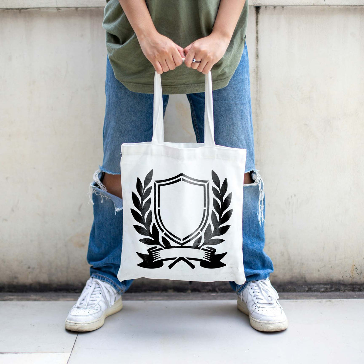 A bold Service Crest Stencil decorates a white tote bag with a shield and laurel emblem