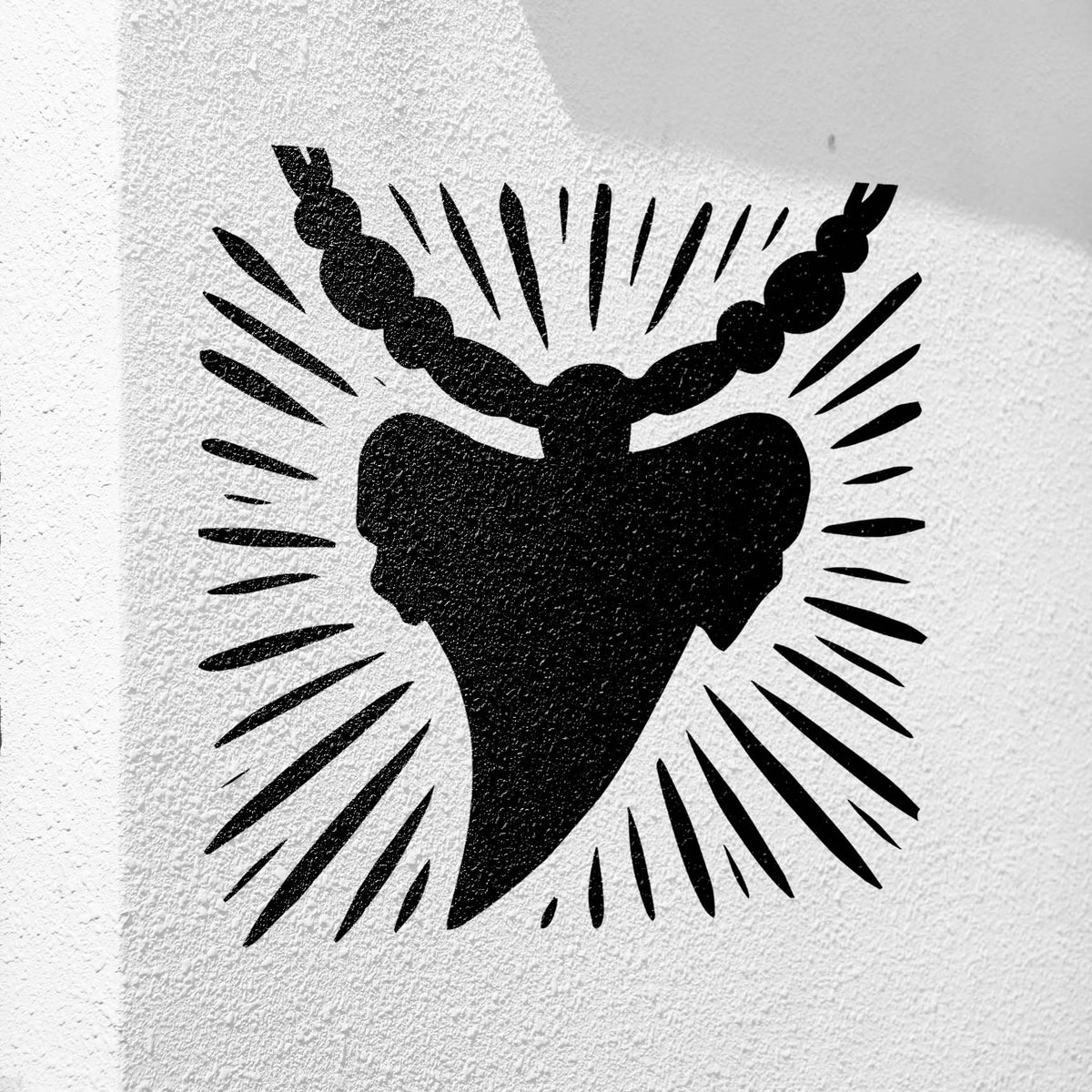 Radiating lines frame the Shark Tooth Necklace Stencil painted on a textured white wall